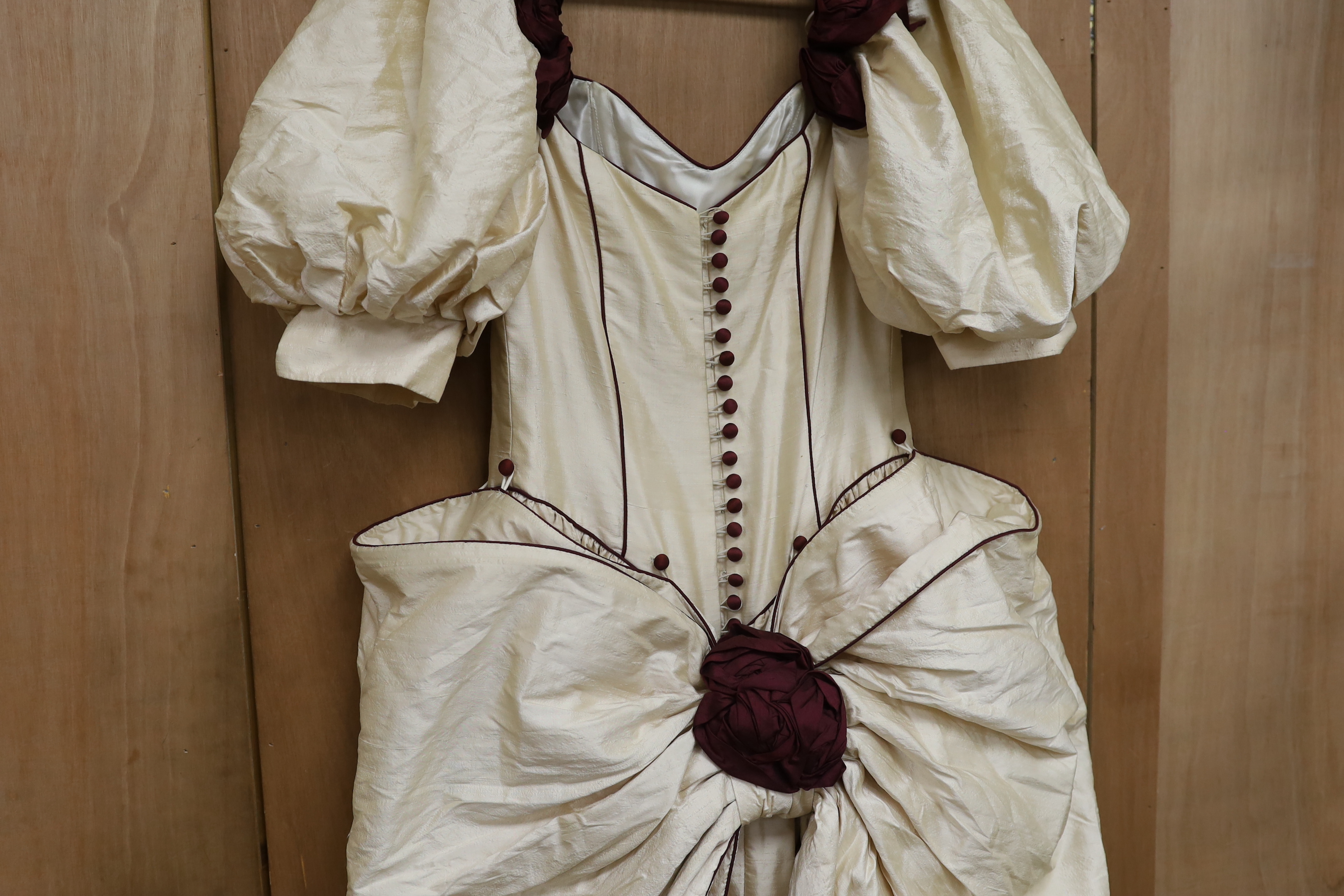 A late 20th century cream silk and burgundy trimmed gown, with bustle, possibly operatic or theatrical